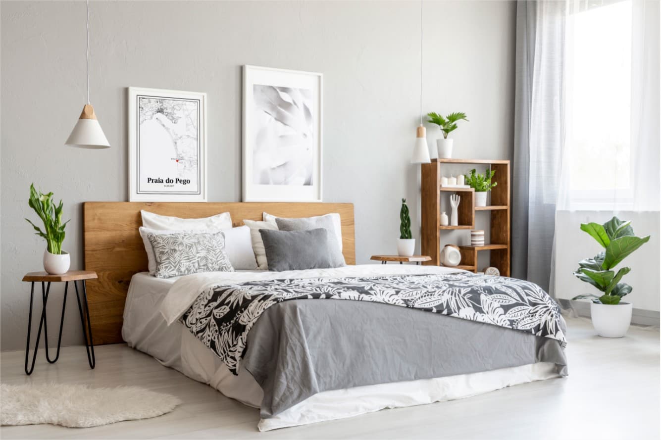 Quarto moderno com cama de madeira, roupa de cama cinza e branca com padrão floral, candeeiro suspenso e prateleira com plantas