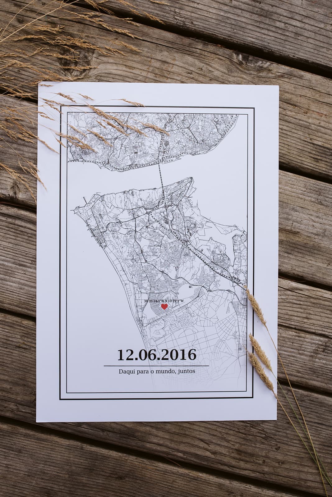 Mapa preto e branco com ponto vermelho, data e texto, sobre madeira rústica com erva seca